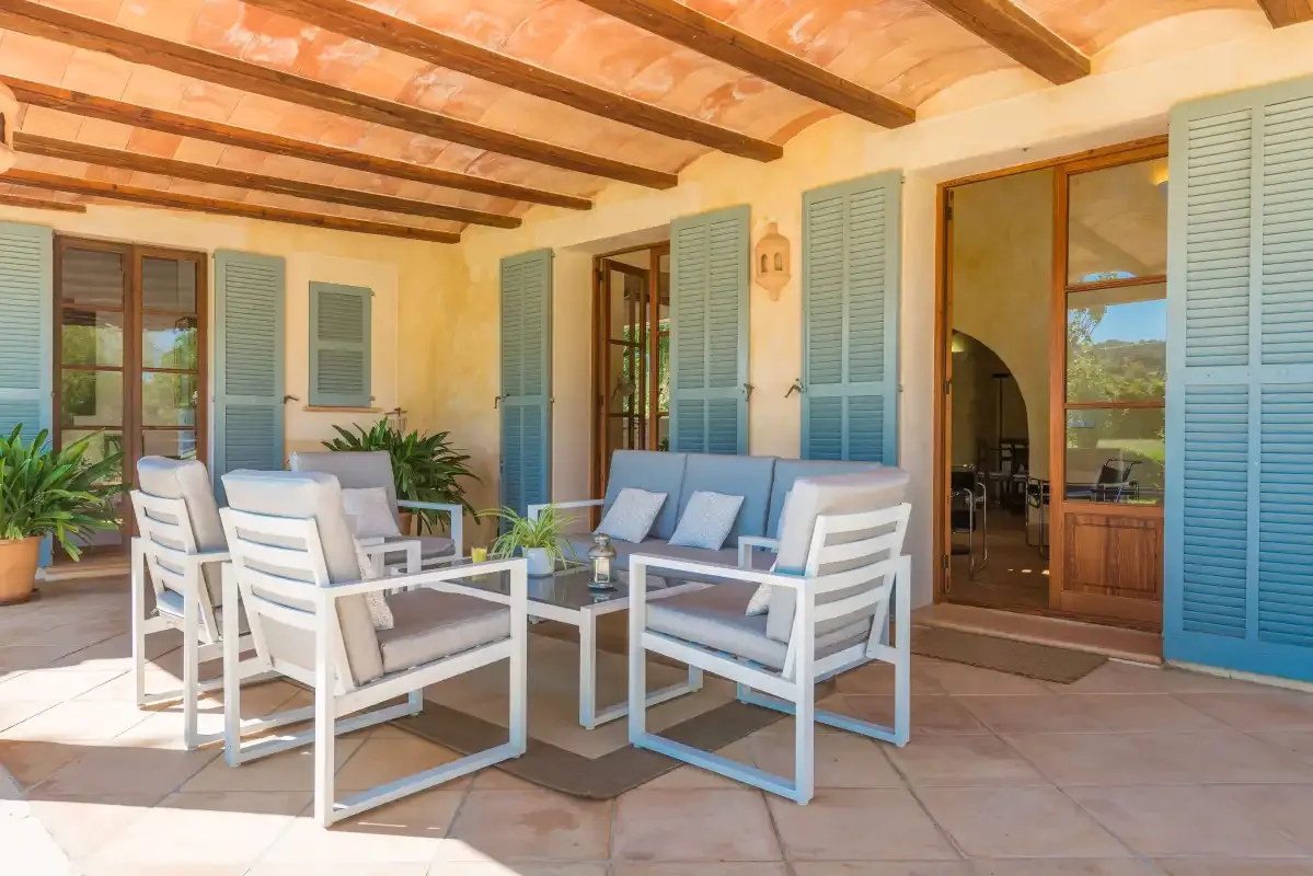 A covered patio with seating and open blue-shuttered doors.