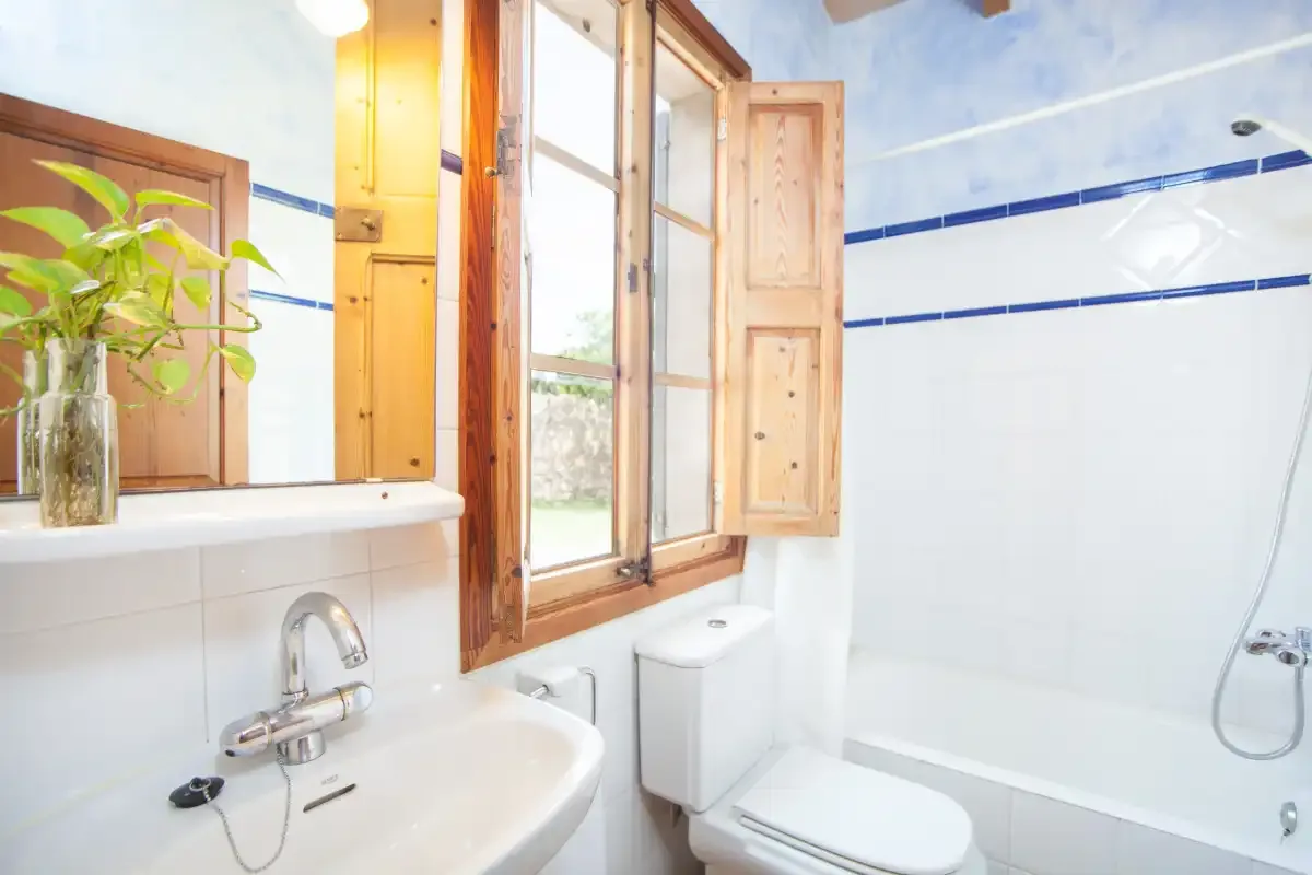 A bathroom with a sink, toilet, and bathtub beside an open window.