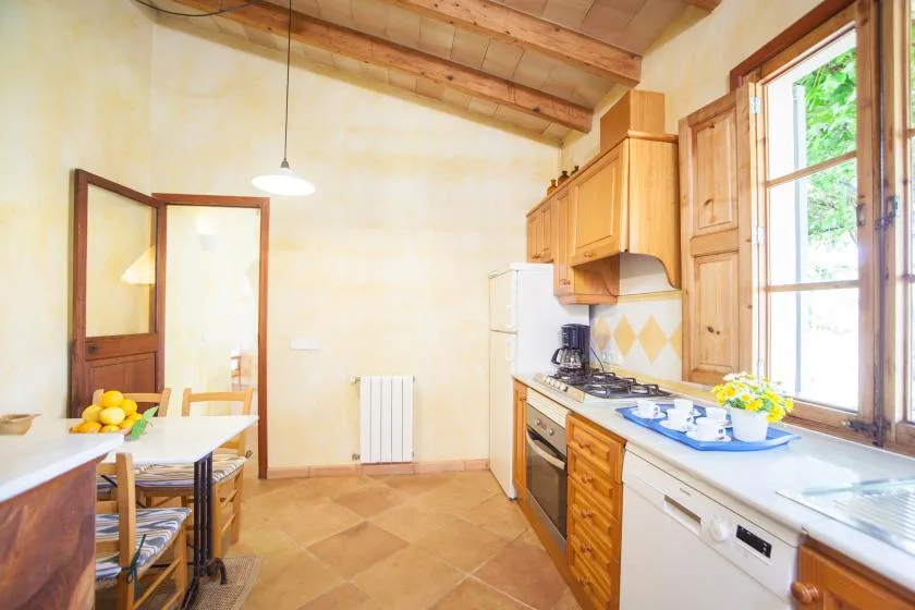 A bright kitchen with wooden cabinets, a dining table, and large windows.