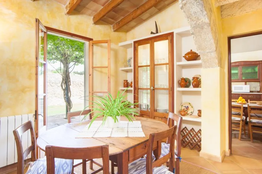 A dining area with a wooden table and chairs beside an open window.