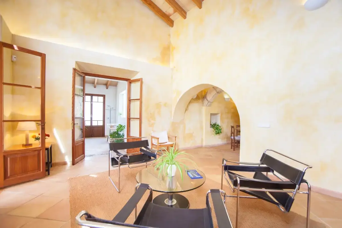 A bright living room with seating, a glass coffee table, and arched openings.