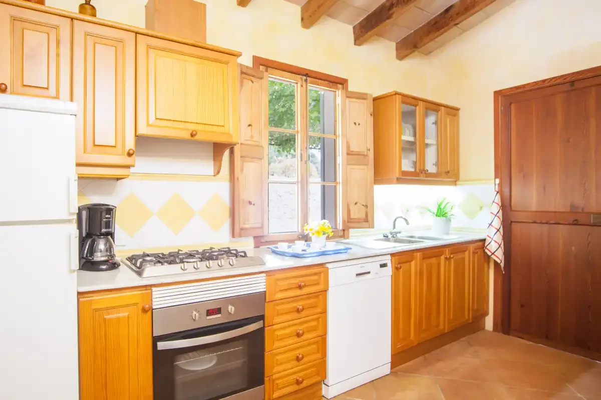 A bright kitchen with wooden cabinets, a stove, and a sink.