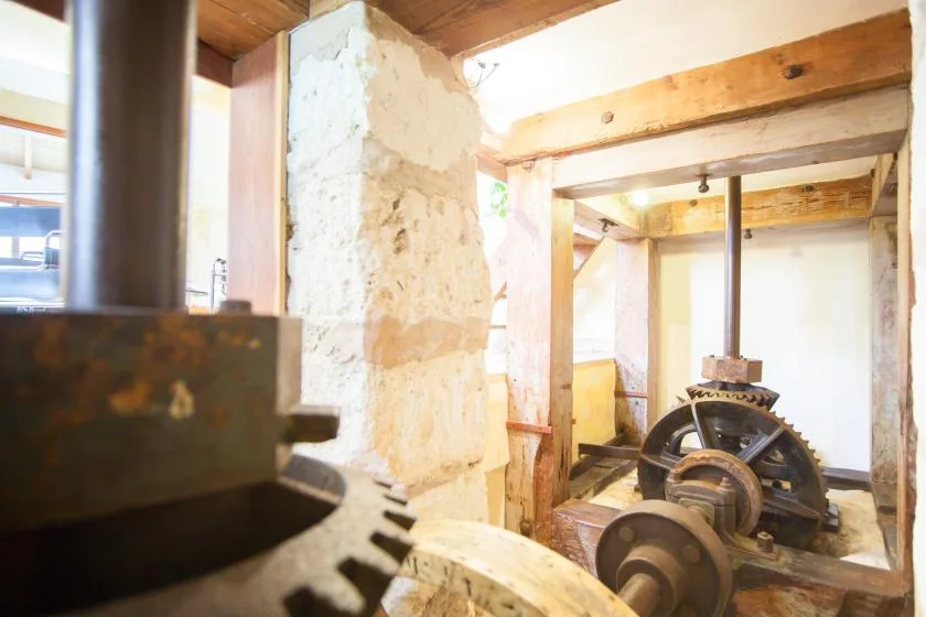An old mill interior with exposed timber beams and milling machinery.