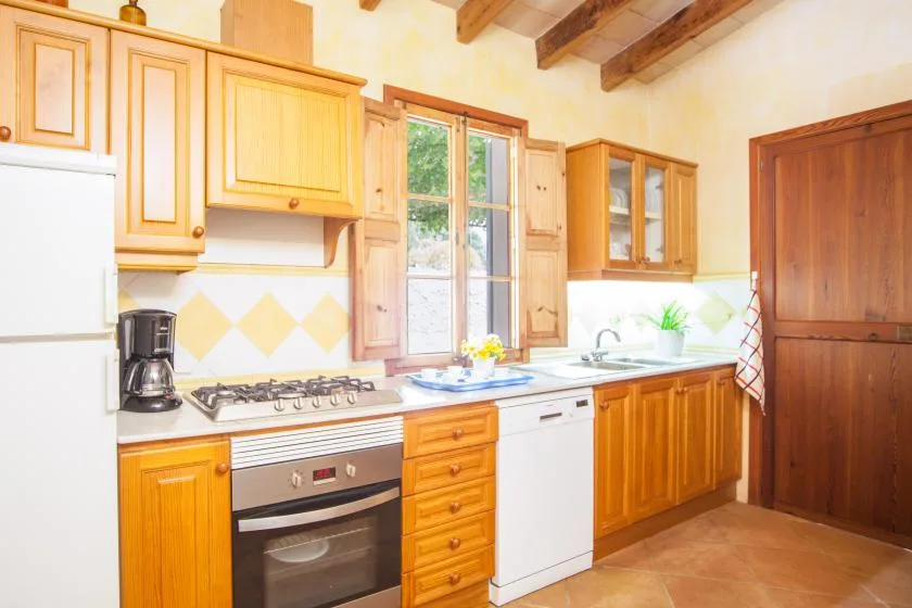 A bright kitchen with wooden cabinets, a window, and a countertop.
