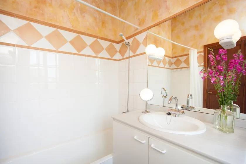 A bathroom with a sink and a tiled shower area.