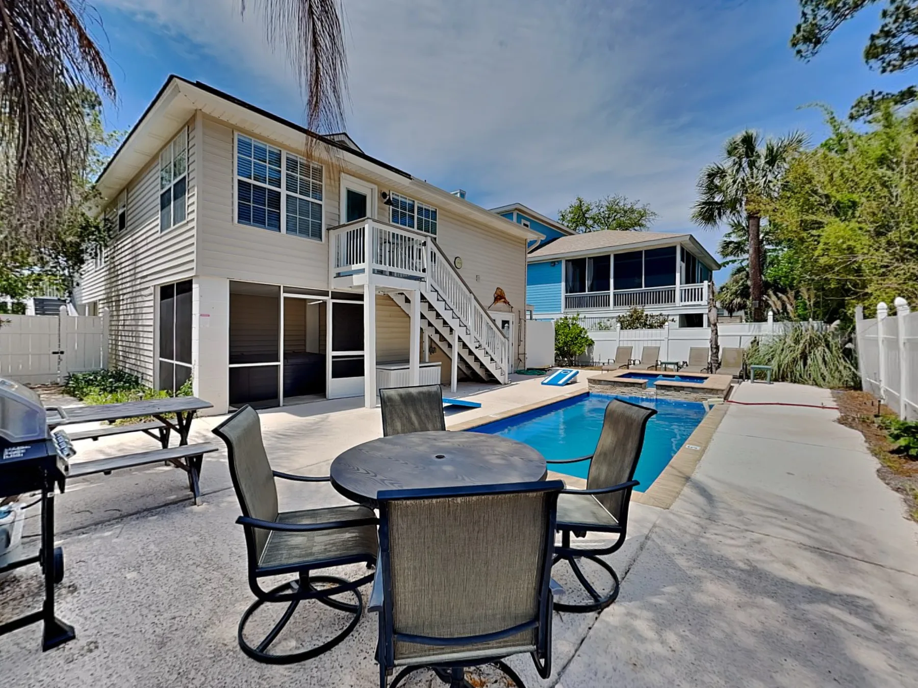 An outdoor pool and patio sit beside two raised coastal-style houses.