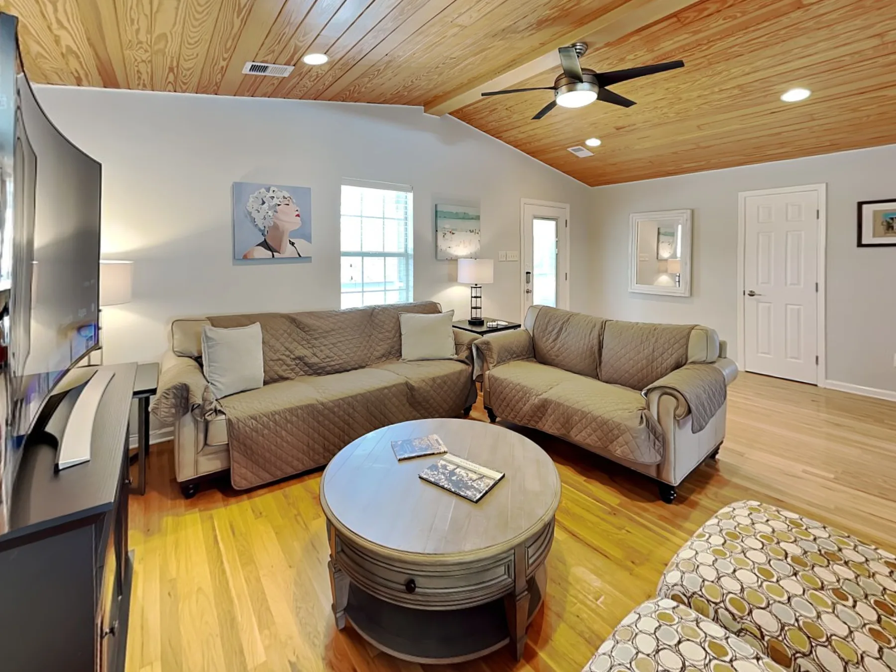 A living room with sectional seating, a round coffee table, and a ceiling fan.