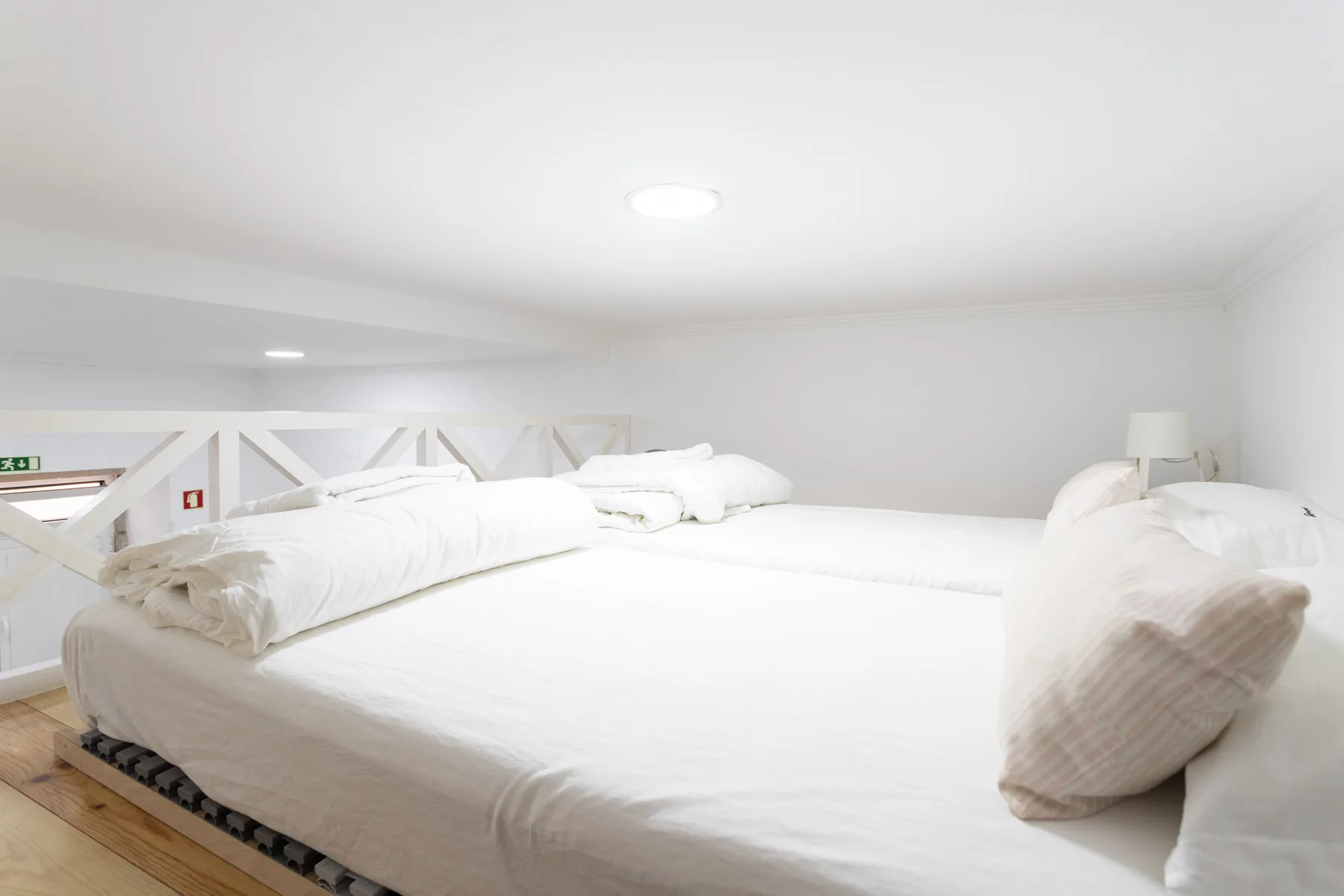 Un dormitorio luminoso tiene una cama grande con ropa de cama blanca y almohadas.