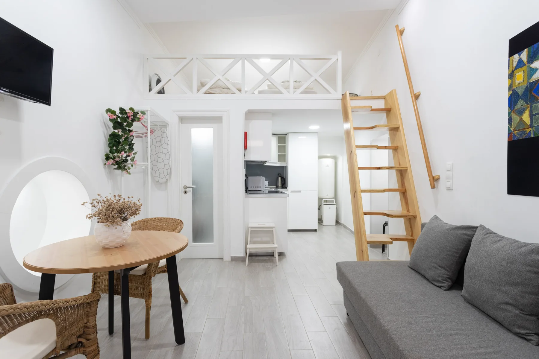 Una luminosa sala de estar con mesa de comedor, asientos y una cocina compacta al fondo.
