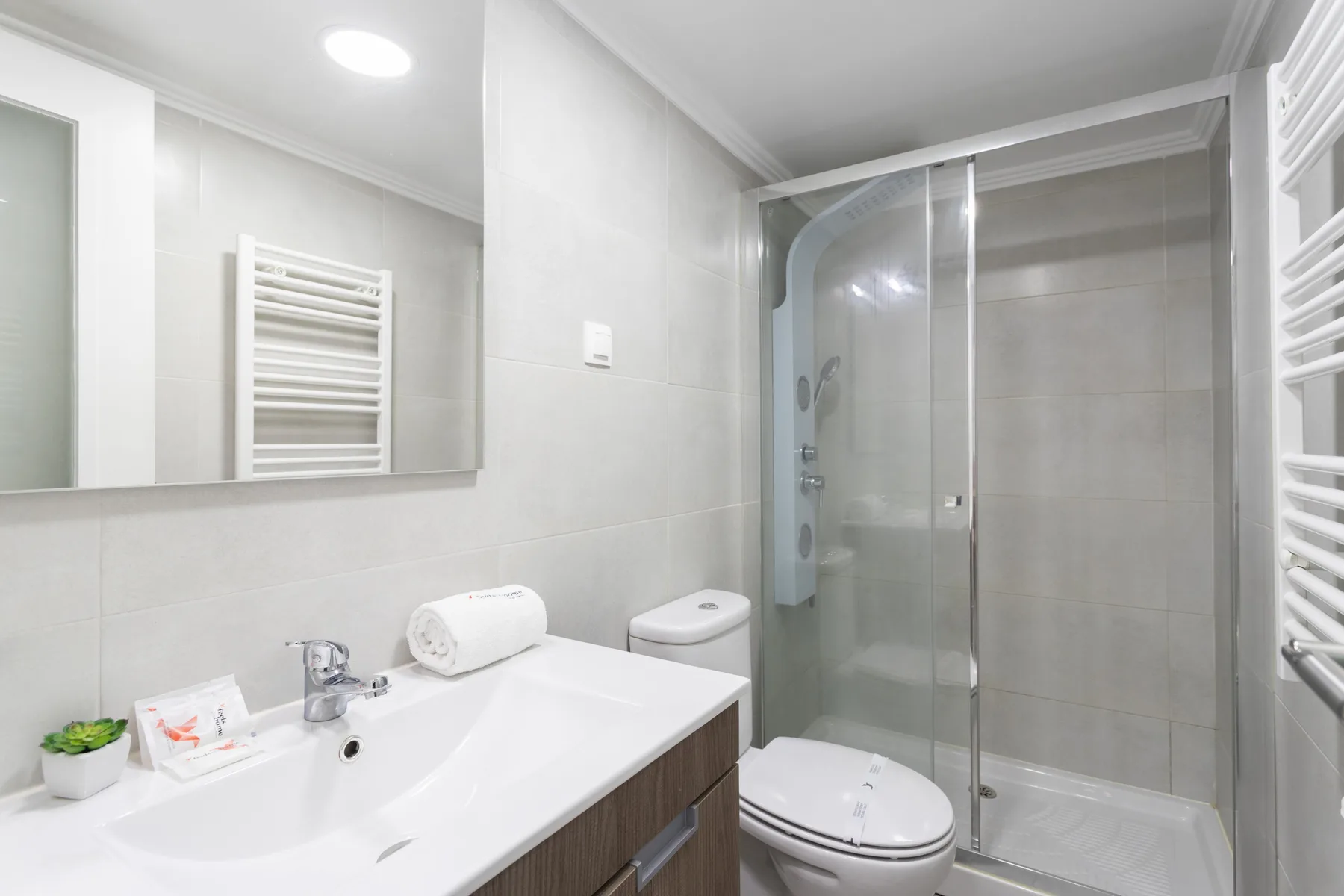 Un baño luminoso con lavabo, inodoro y ducha de vidrio.