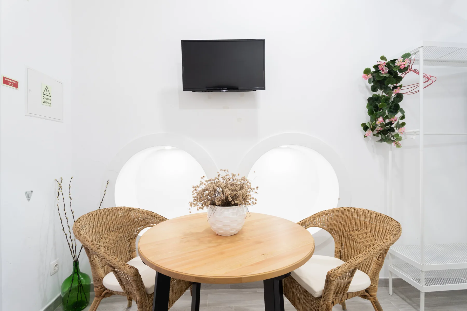 Una pequeña zona de comedor con una mesa redonda de madera y asientos de mimbre.