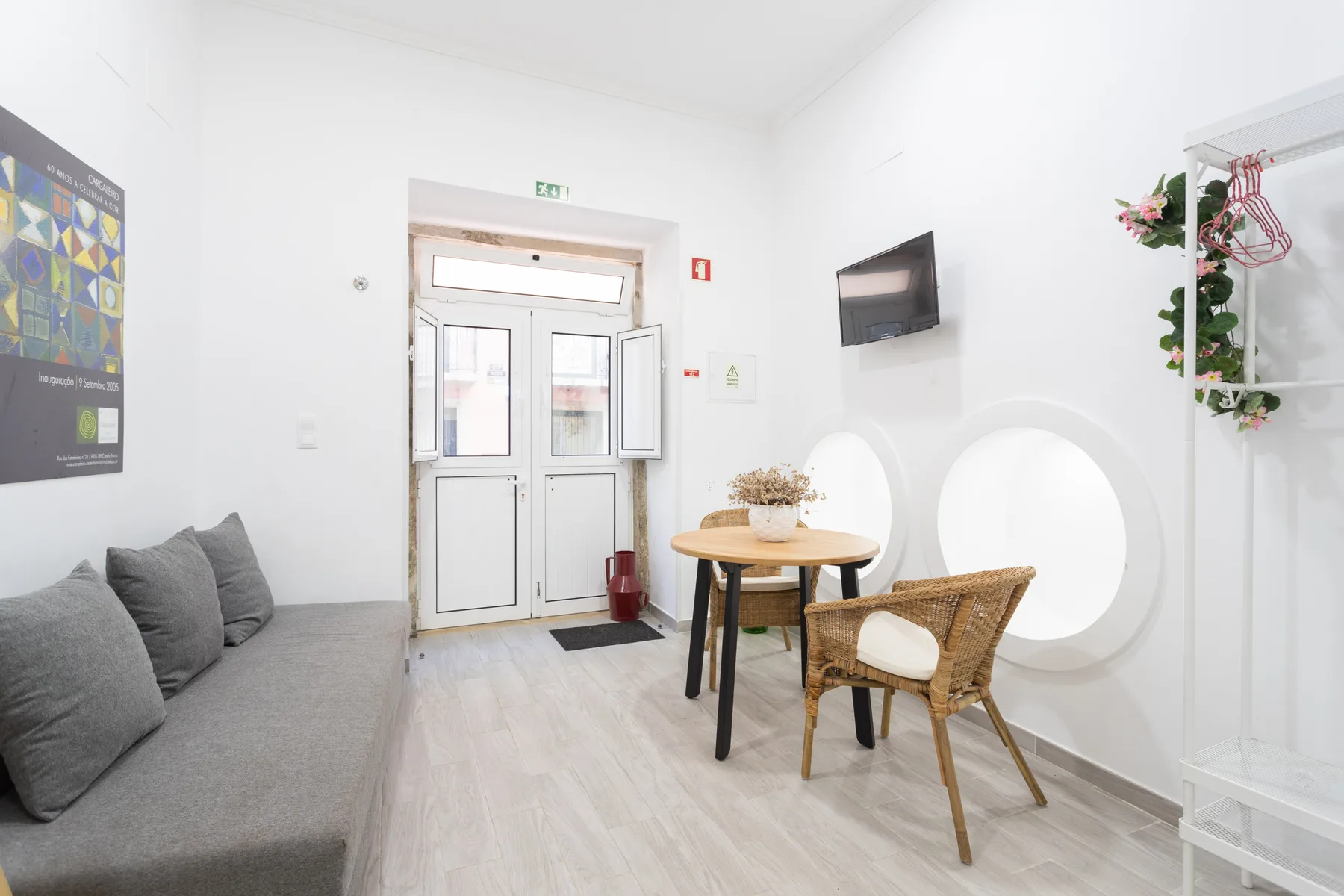 Una zona de estar luminosa con un sofá gris y una mesa pequeña junto a la entrada.