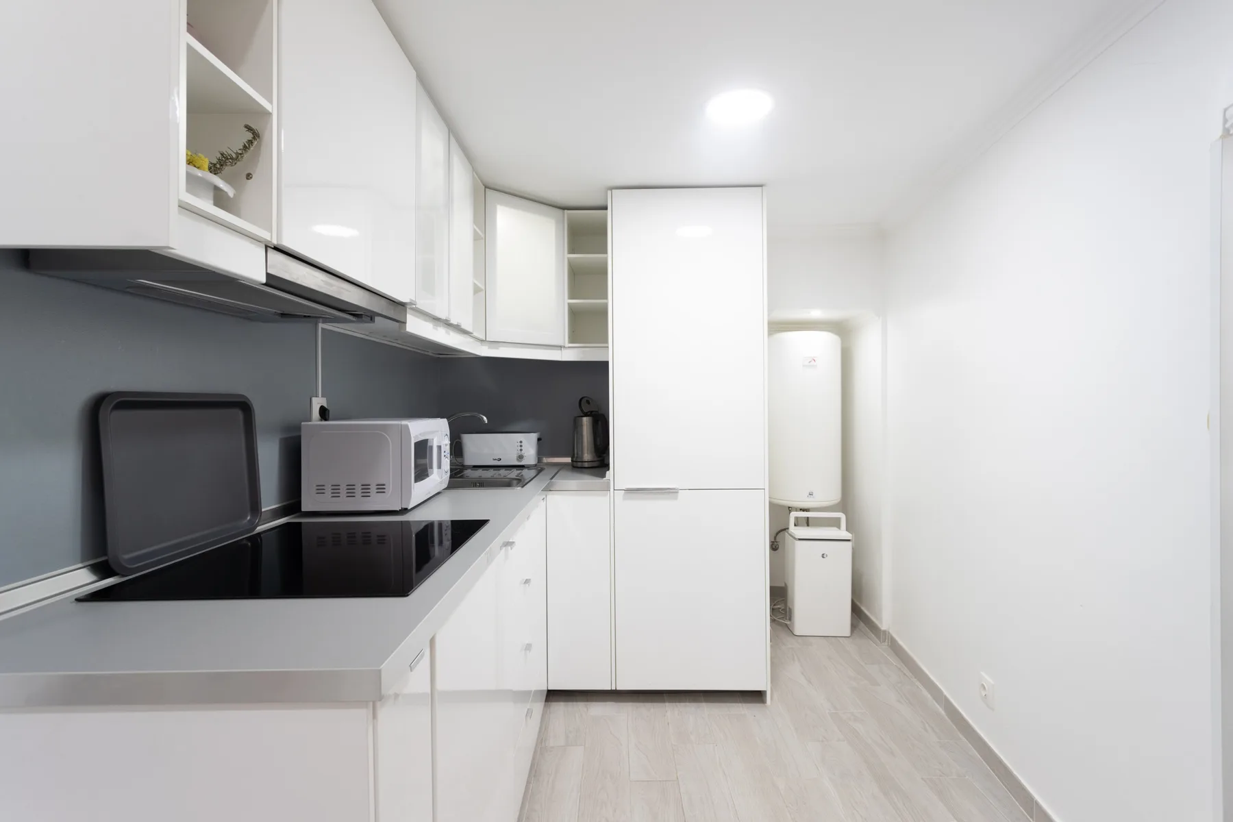 Una cocina compacta con gabinetes blancos, una encimera y electrodomésticos.