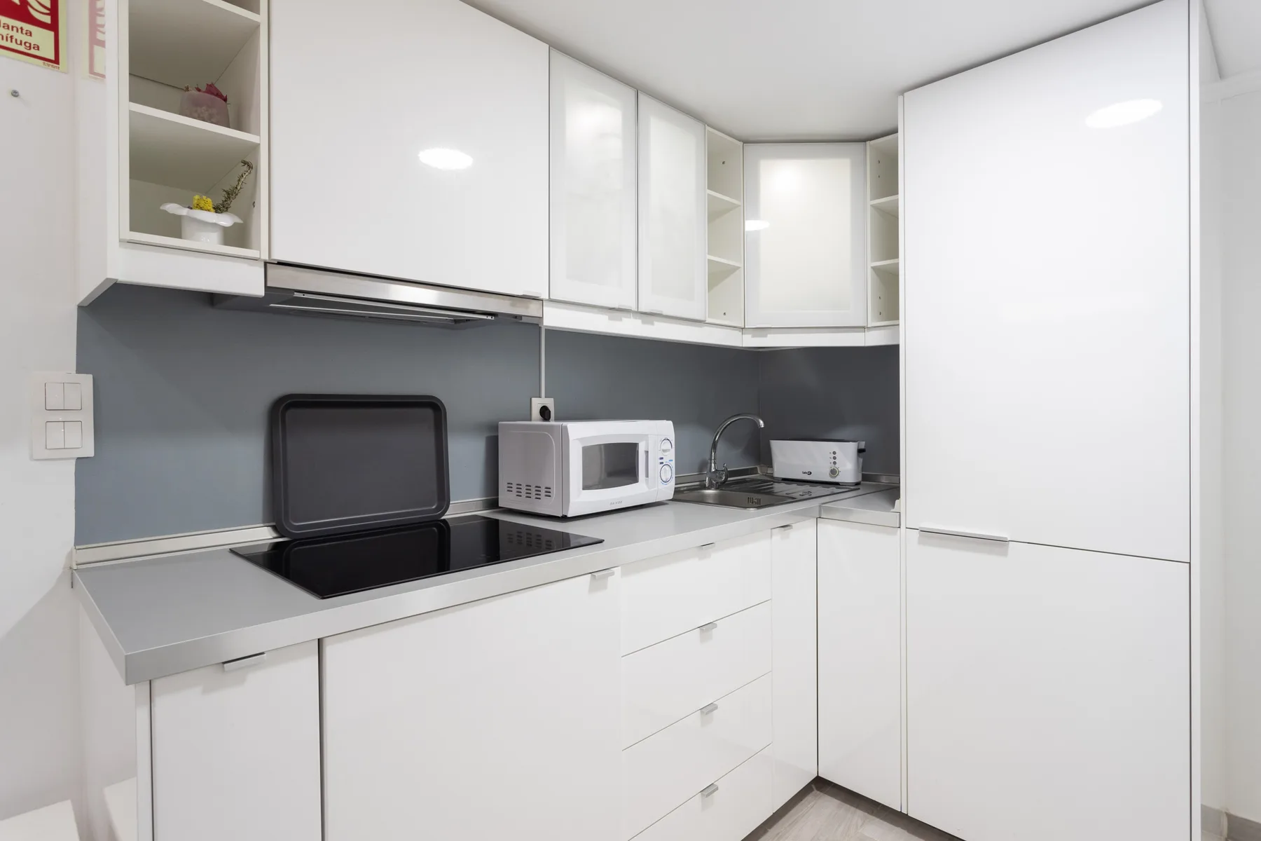 Una cocina moderna y luminosa con armarios blancos y una encimera oscura.