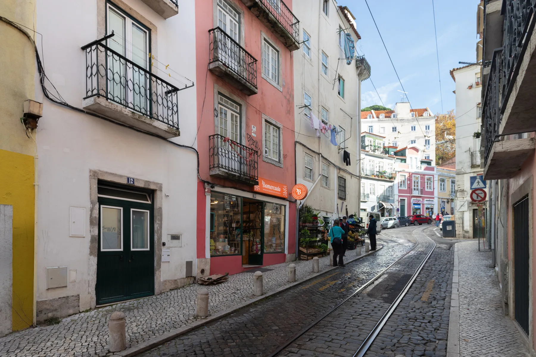 Una calle adoquinada pasa entre edificios coloridos, con vías de tranvía sobre la calzada.