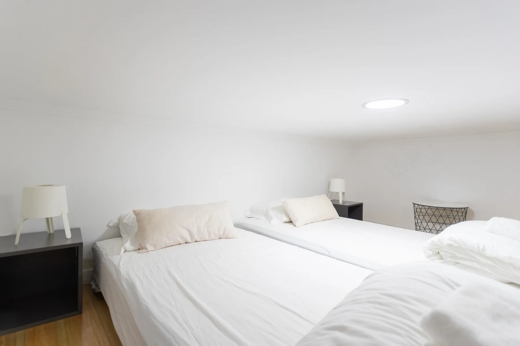 Un dormitorio luminoso con dos camas vestidas con ropa de cama blanca.