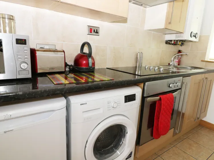 A compact kitchen with a washing machine beneath the counter and a stove.