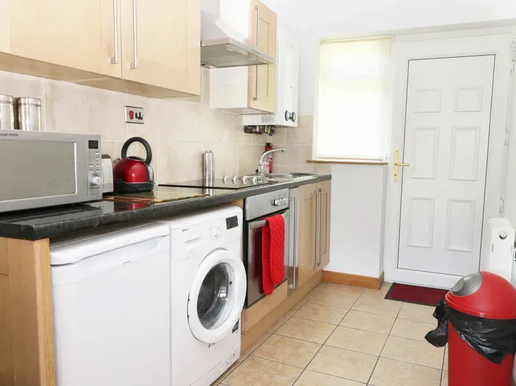 A compact kitchen with a countertop, sink, and laundry appliances.