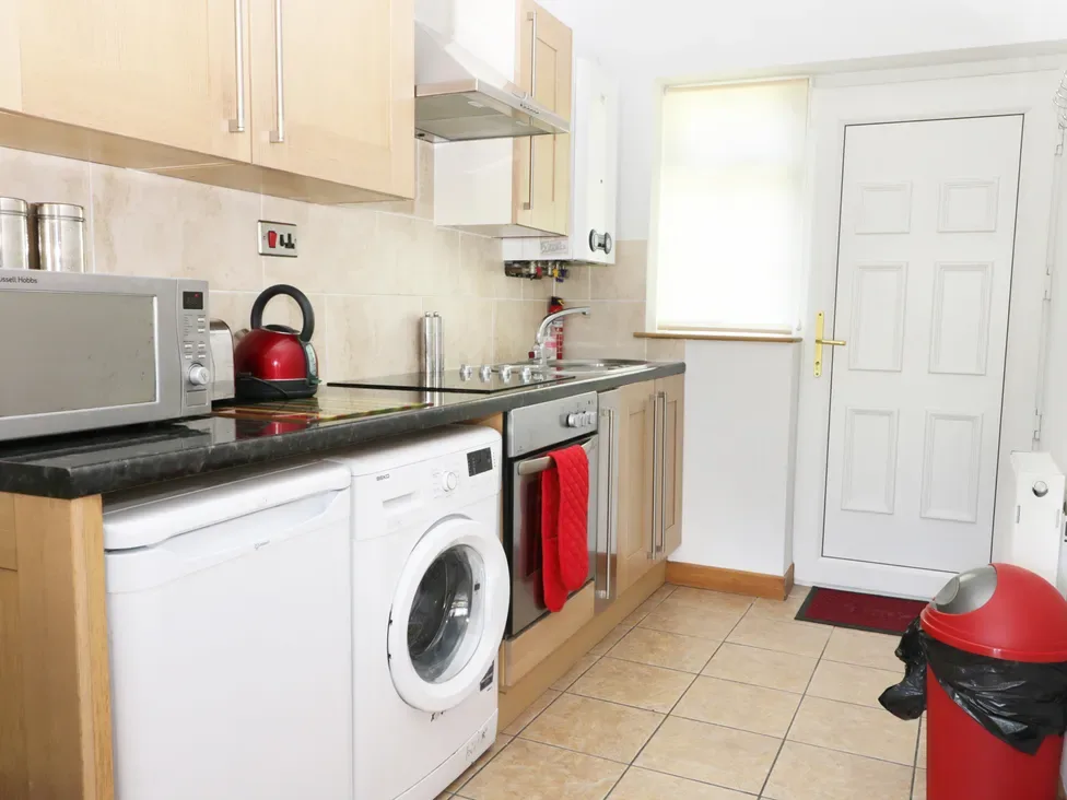 A kitchen with appliances including a microwave kettle washing machine and oven with red towel at The Bungalow in Dunnington