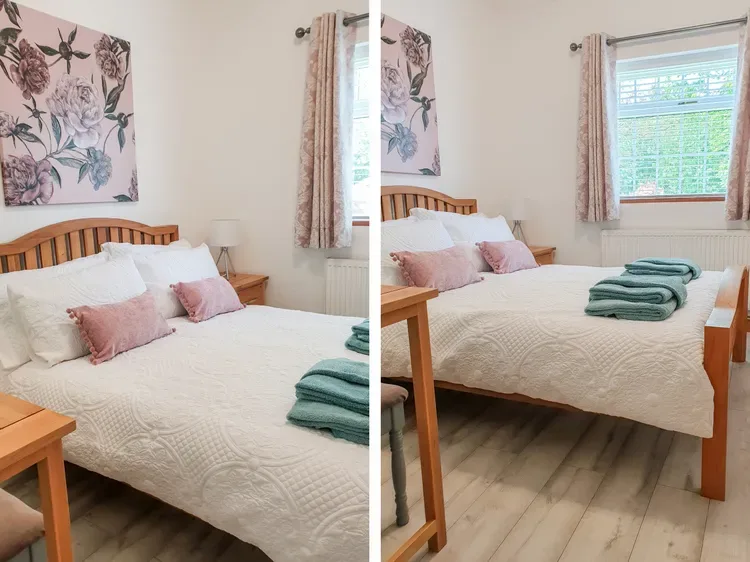 A bedroom with a neatly made bed, floral wall art, and a window.