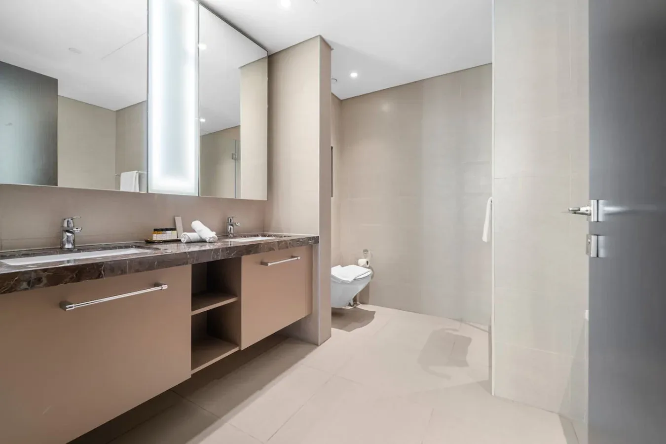 A modern bathroom with a long vanity and walk-in shower.