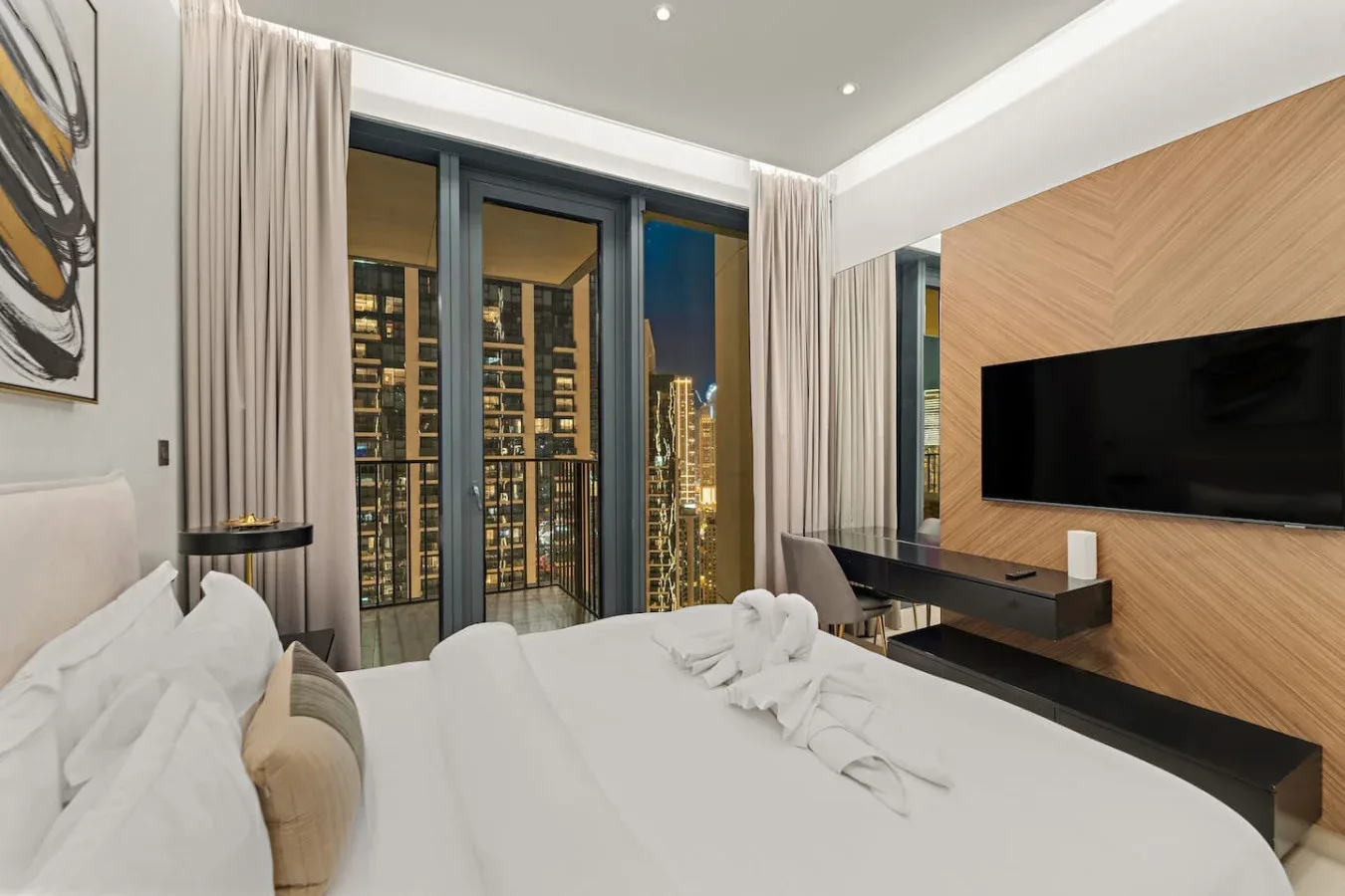 A bedroom with a bed, floor-to-ceiling windows, and a wall-mounted television.
