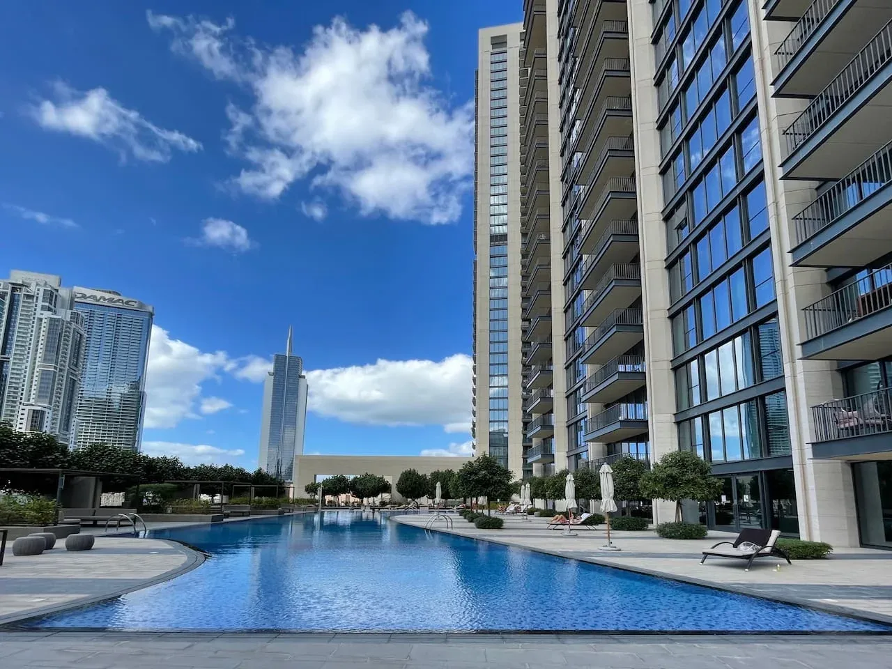 An outdoor swimming pool sits beside a modern high-rise building.