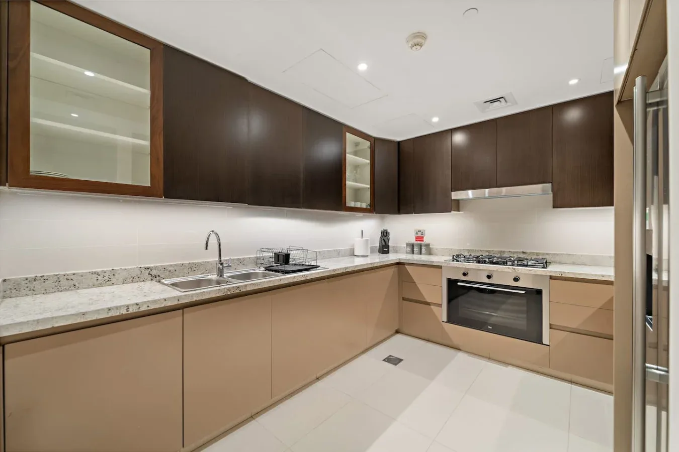 A modern kitchen with light cabinets and dark upper cupboards.