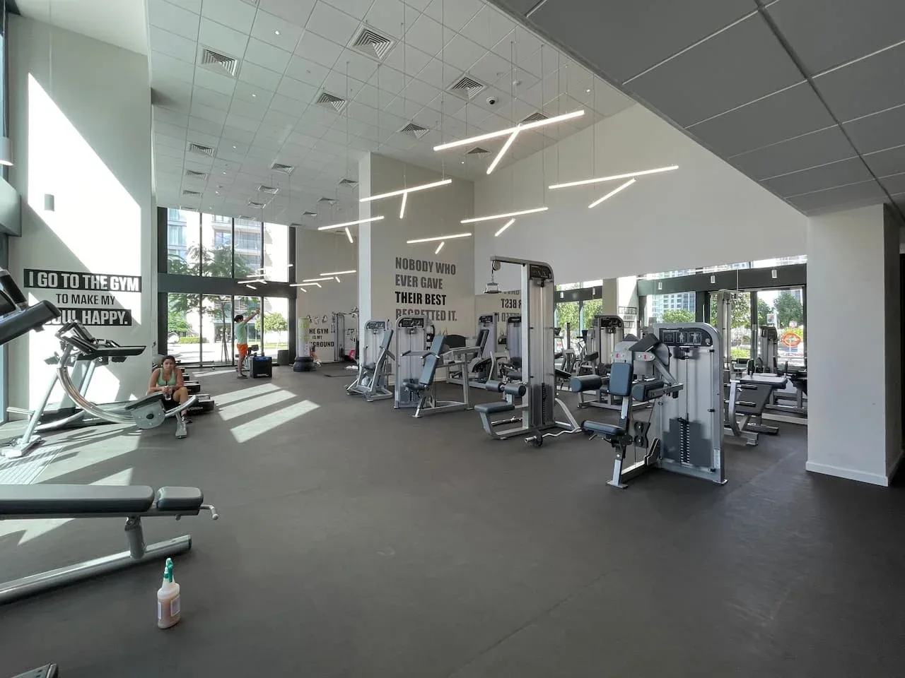A bright gym with exercise machines and large windows.