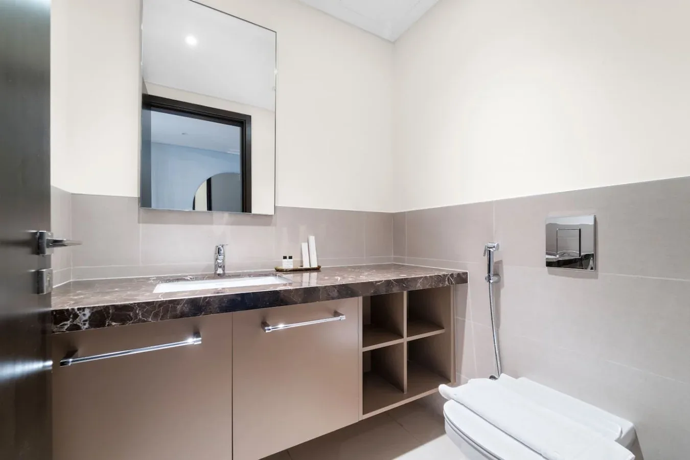A modern bathroom with a wide vanity, mirror, and toilet.