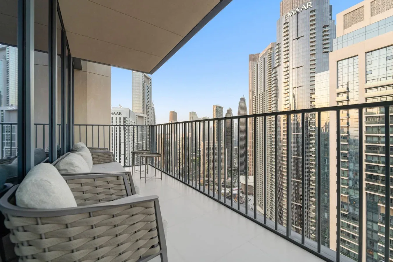 A balcony with cushioned seating overlooks a city skyline.