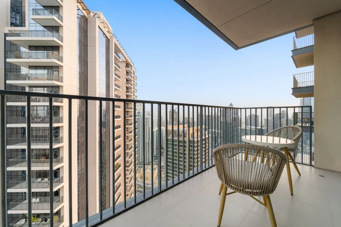 A balcony with outdoor seating overlooks nearby buildings.