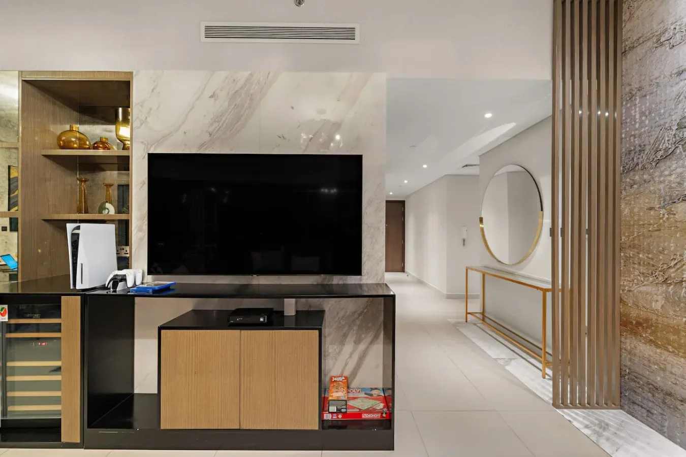 A modern living area features a large television beside a bright hallway.