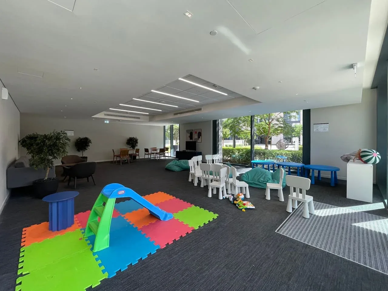A bright indoor play area with colorful foam mats and child-sized seating.