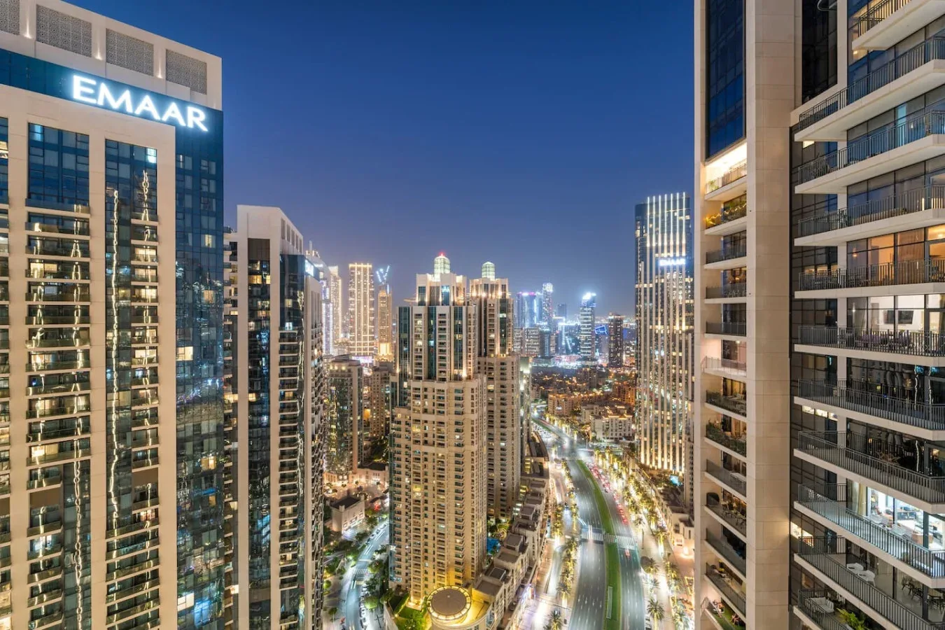 Nighttime city skyline viewed between illuminated high-rise buildings.