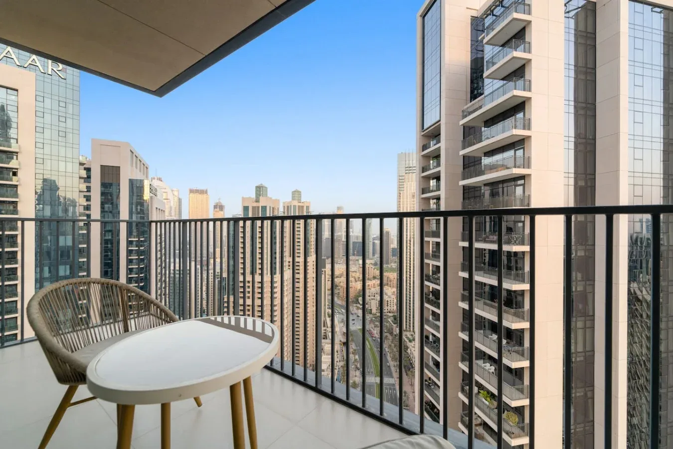 A balcony with outdoor seating overlooks a city skyline.