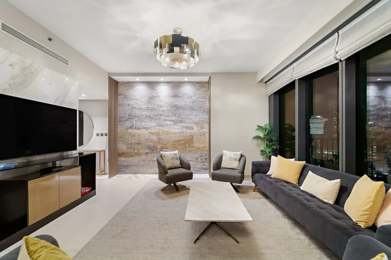 A modern living room with seating arranged around a low table beside large windows.