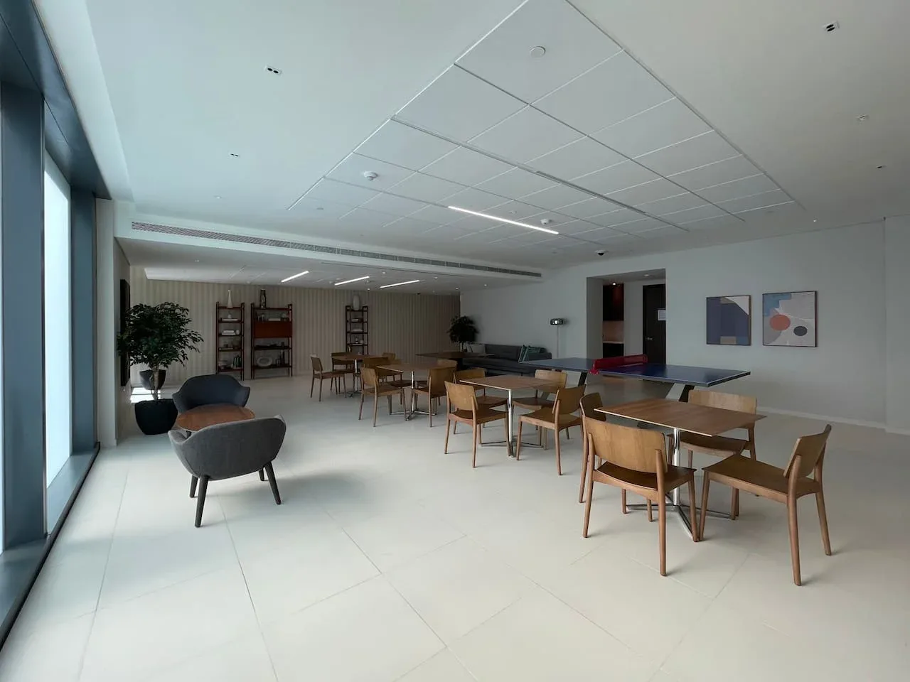 A spacious dining area with wooden tables and seating beside large windows.