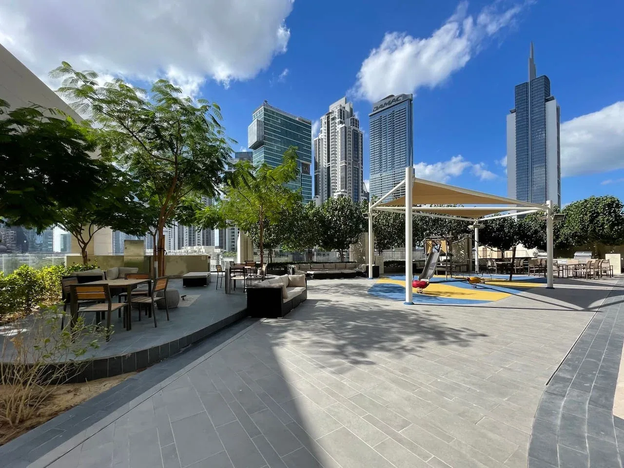 A landscaped rooftop terrace with outdoor seating and tall city buildings in the background.