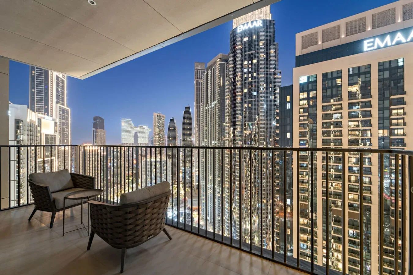 A balcony overlooks illuminated high-rise buildings at night.