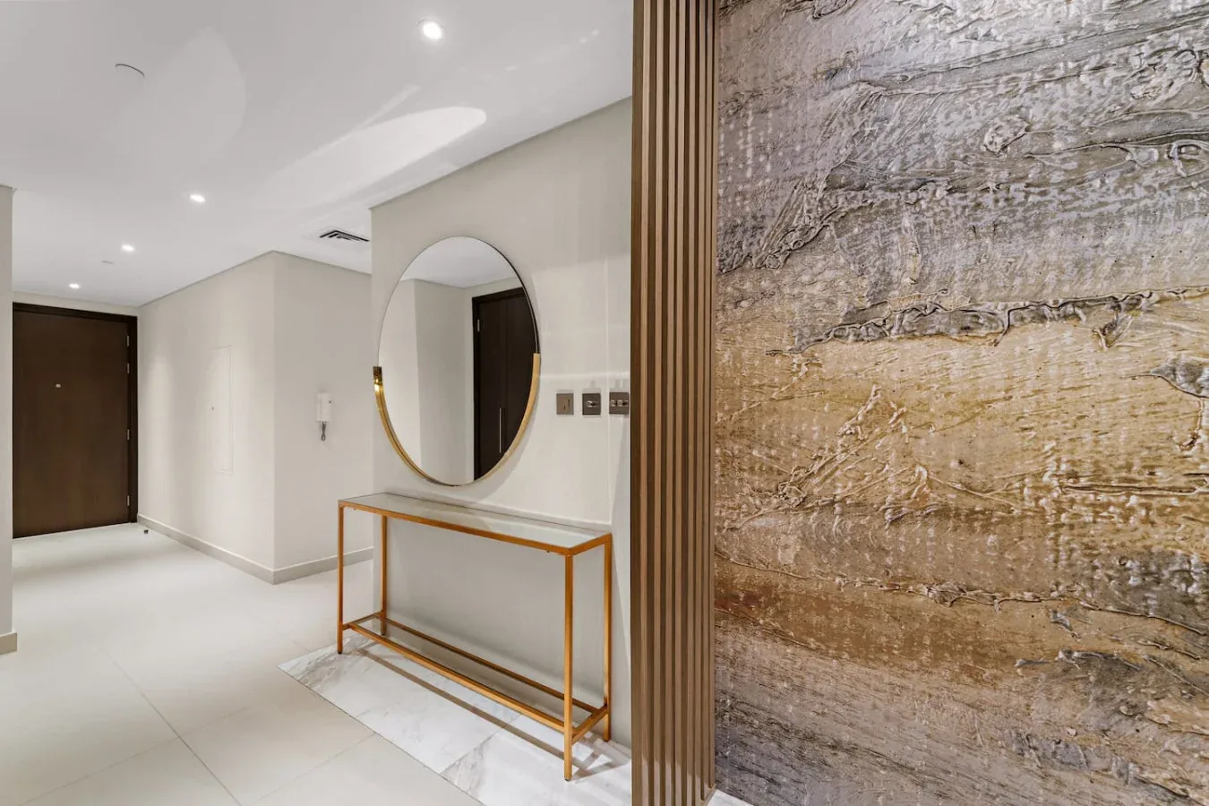 A bright entry hall features a round mirror above a narrow console table.