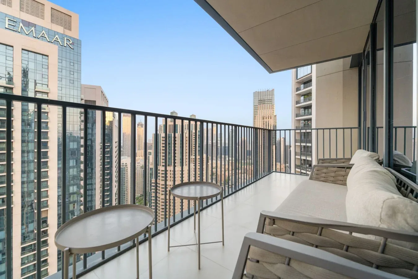 A balcony with seating and small tables overlooks a cluster of high-rise buildings.