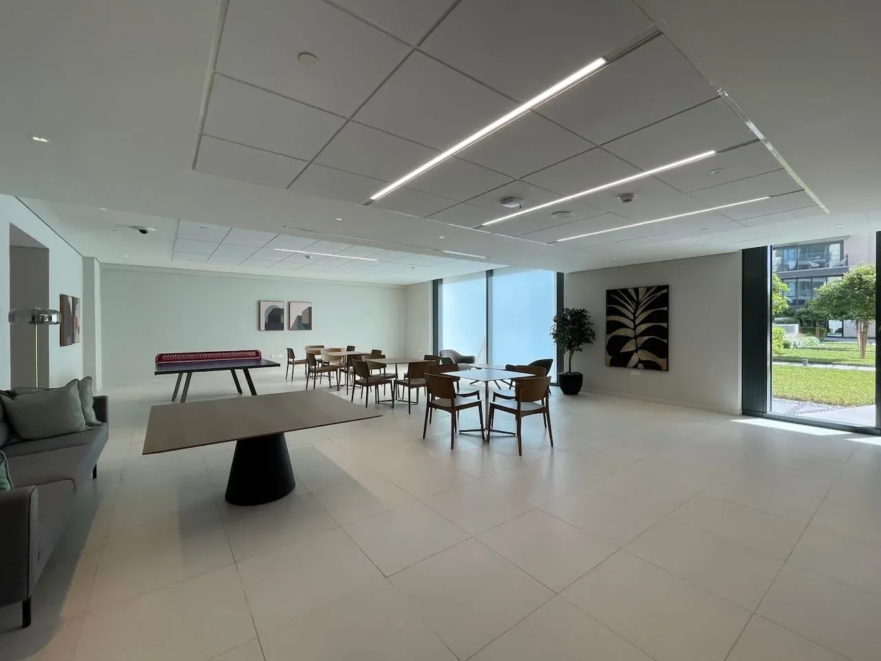 A spacious lounge with seating and tables beside large windows.