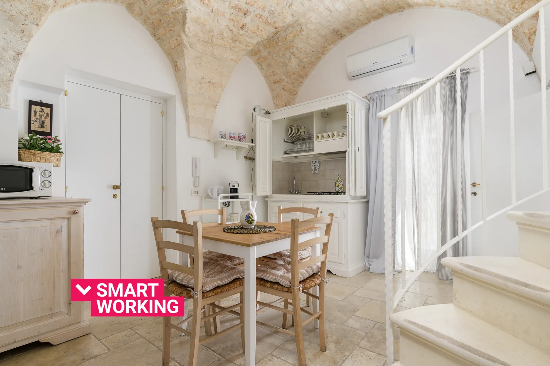 A bright dining area with a wooden table beneath a vaulted stone ceiling.