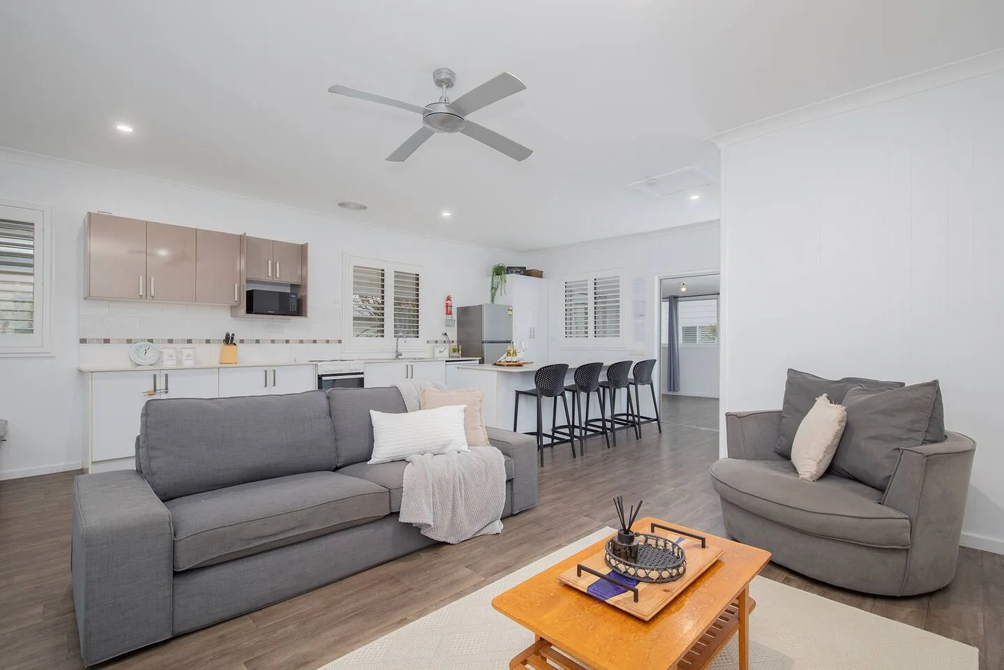 An open-plan living room and kitchen with gray seating and a dining counter.