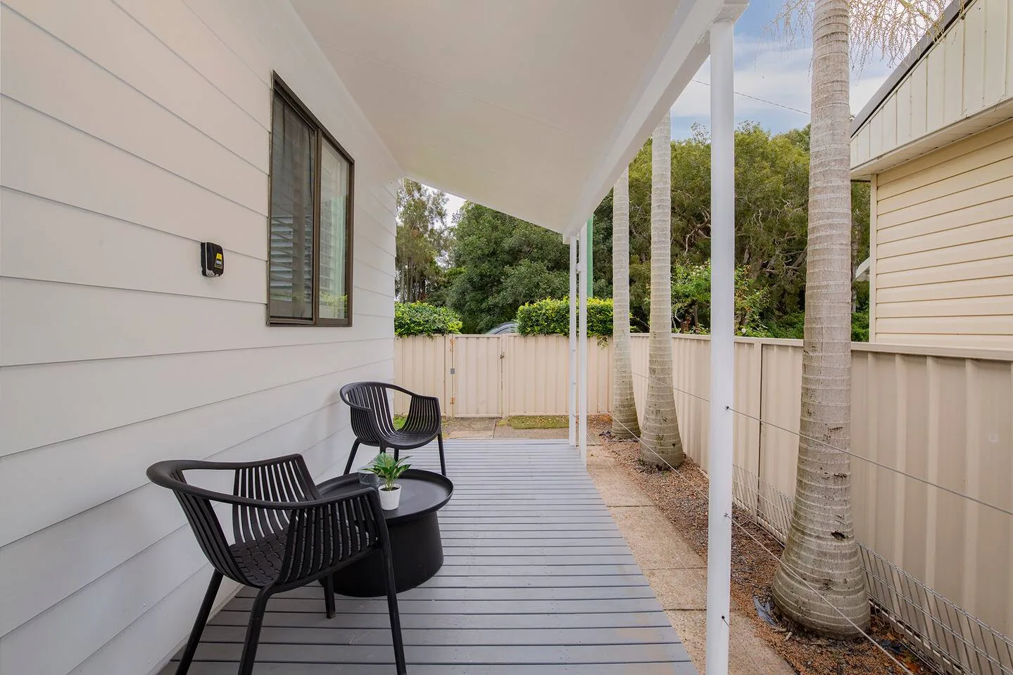 A covered porch with outdoor seating and a view of the garden.