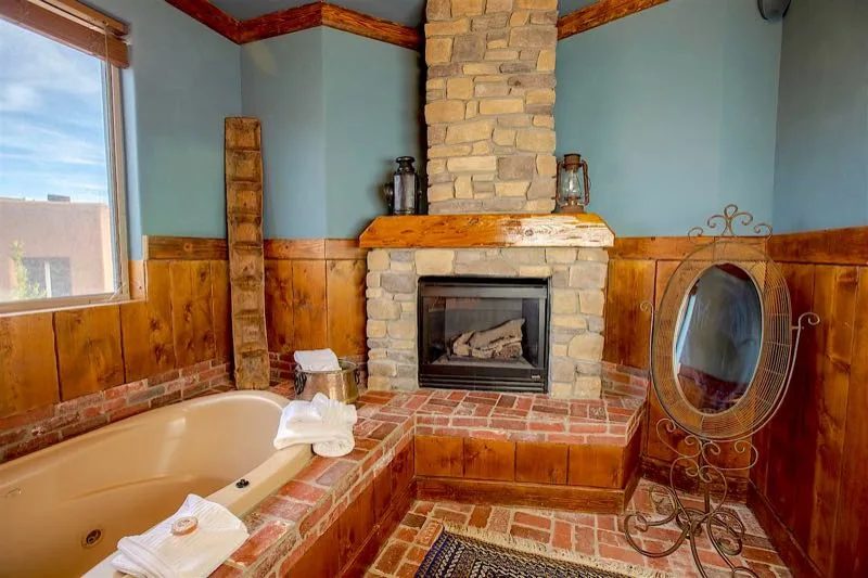 Bañera de hidromasaje de Timbers junto a una chimenea de piedra
