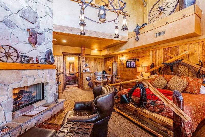 Sala de estar de Silver Spur de estilo del oeste con chimenea de piedra y sillones de cuero