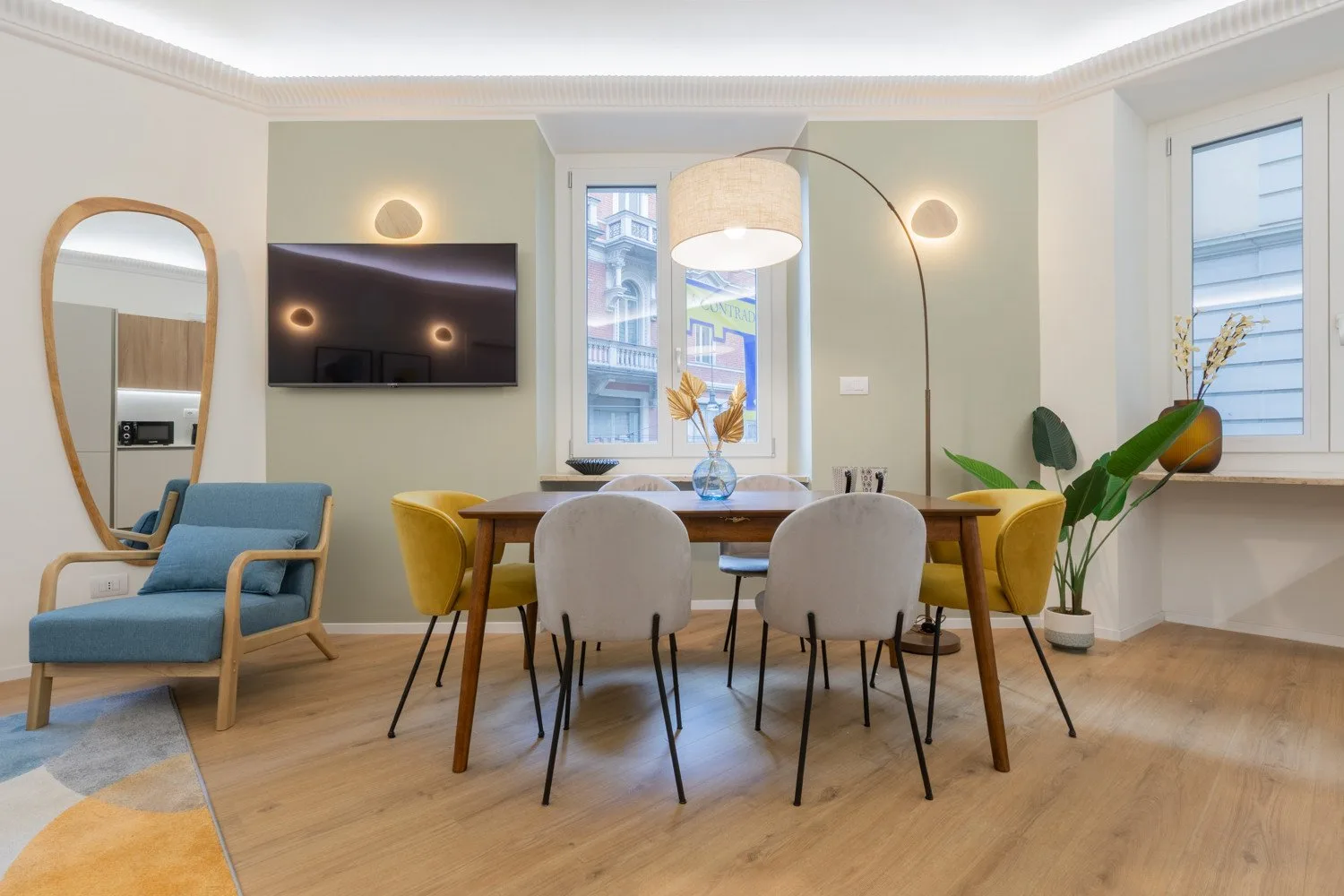 Un comedor con una mesa de madera, asientos tapizados y ventanas.