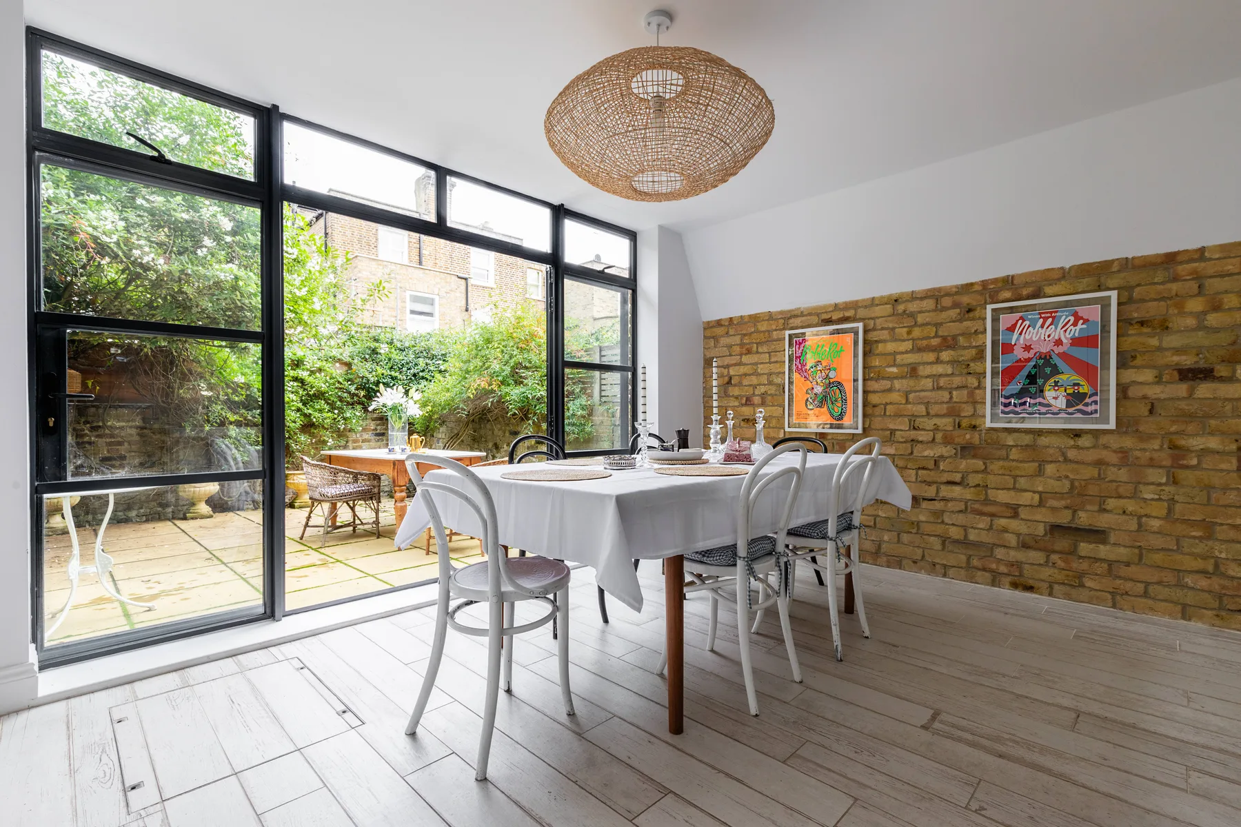 Comedor con una mesa junto a grandes ventanales que dan a un patio frondoso.